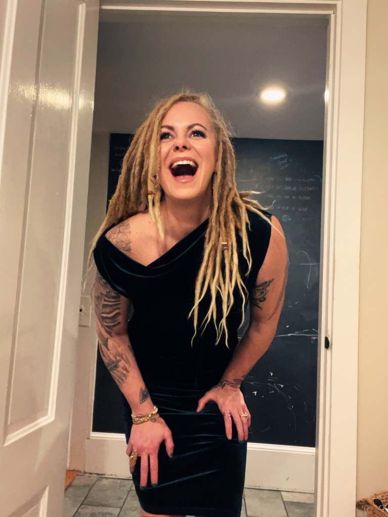 Marta Kagan laughing in a doorway in a green velvet dress